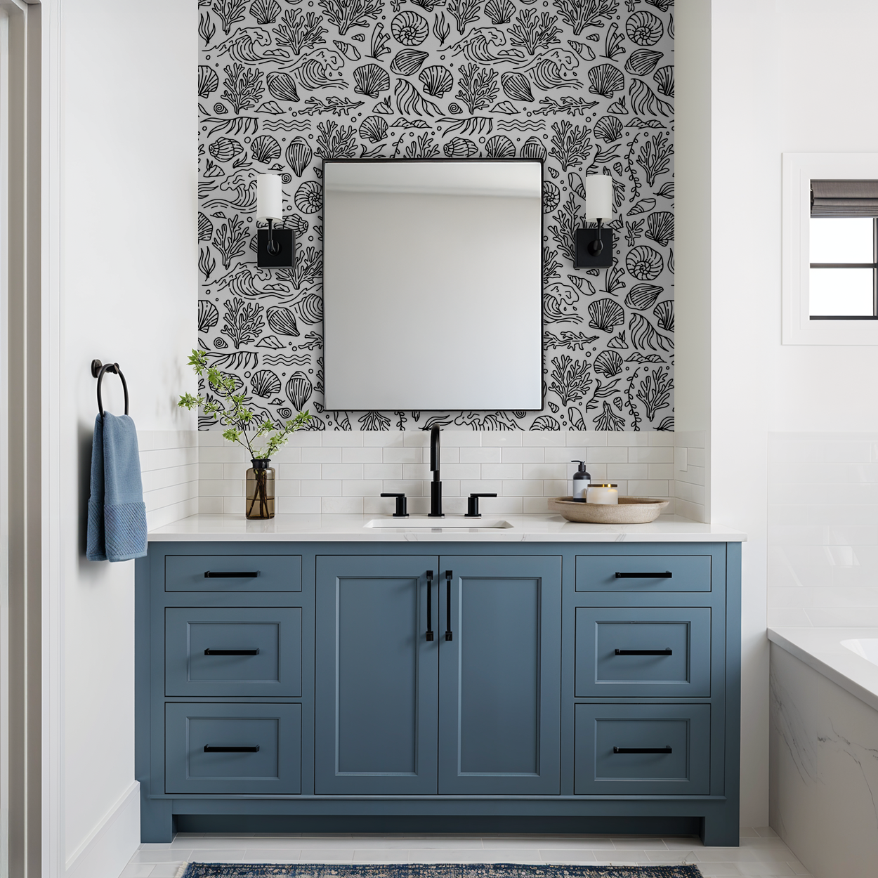 Black and white marine motif wallpaper in a modern bathroom with blue vanity.