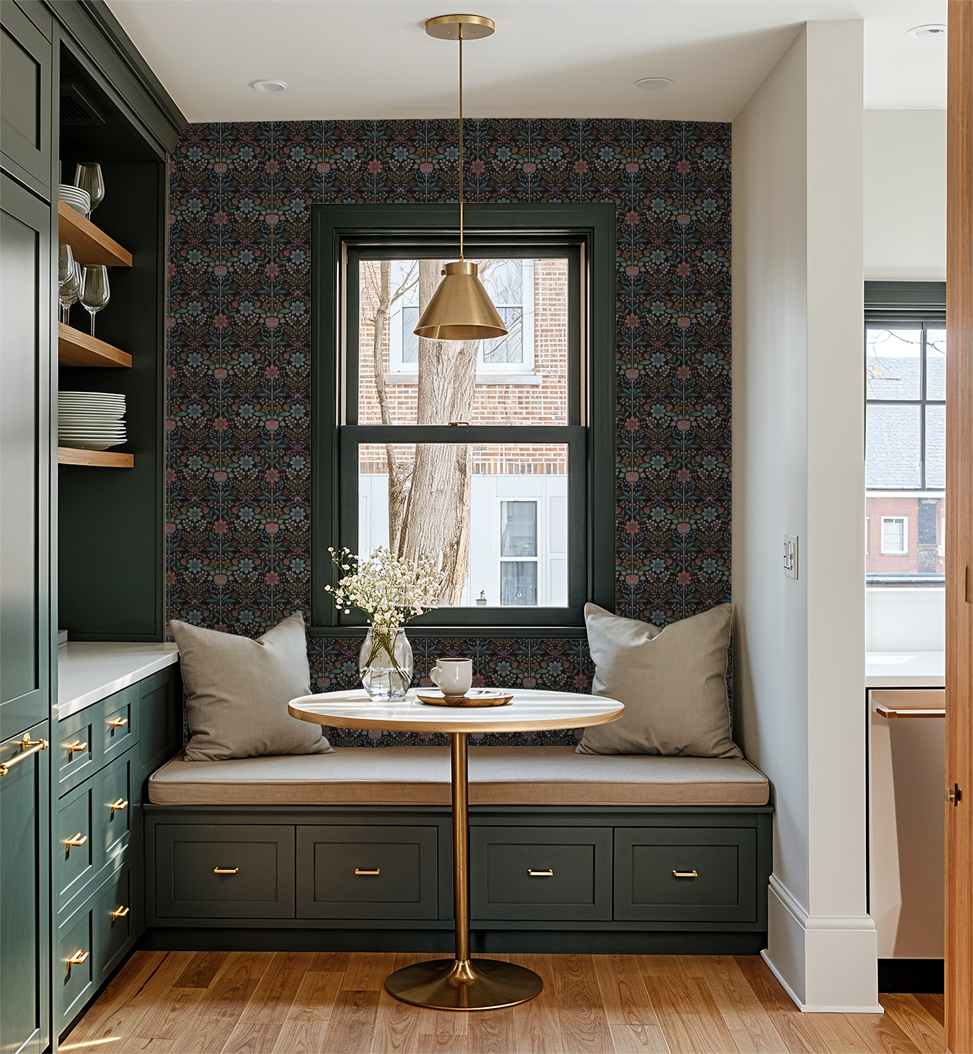 Bloomshire floral wallpaper in cozy breakfast nook with green cabinets and gold accents.