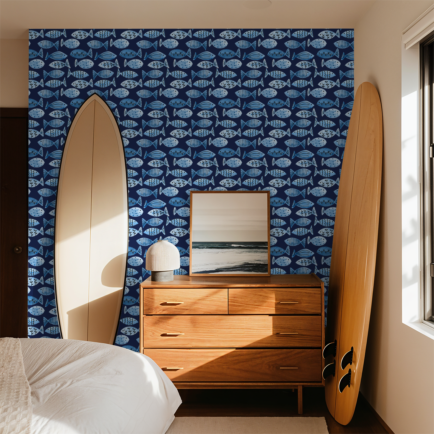 Blue fish pattern wallpaper in coastal bedroom with surfboards and wooden dresser.