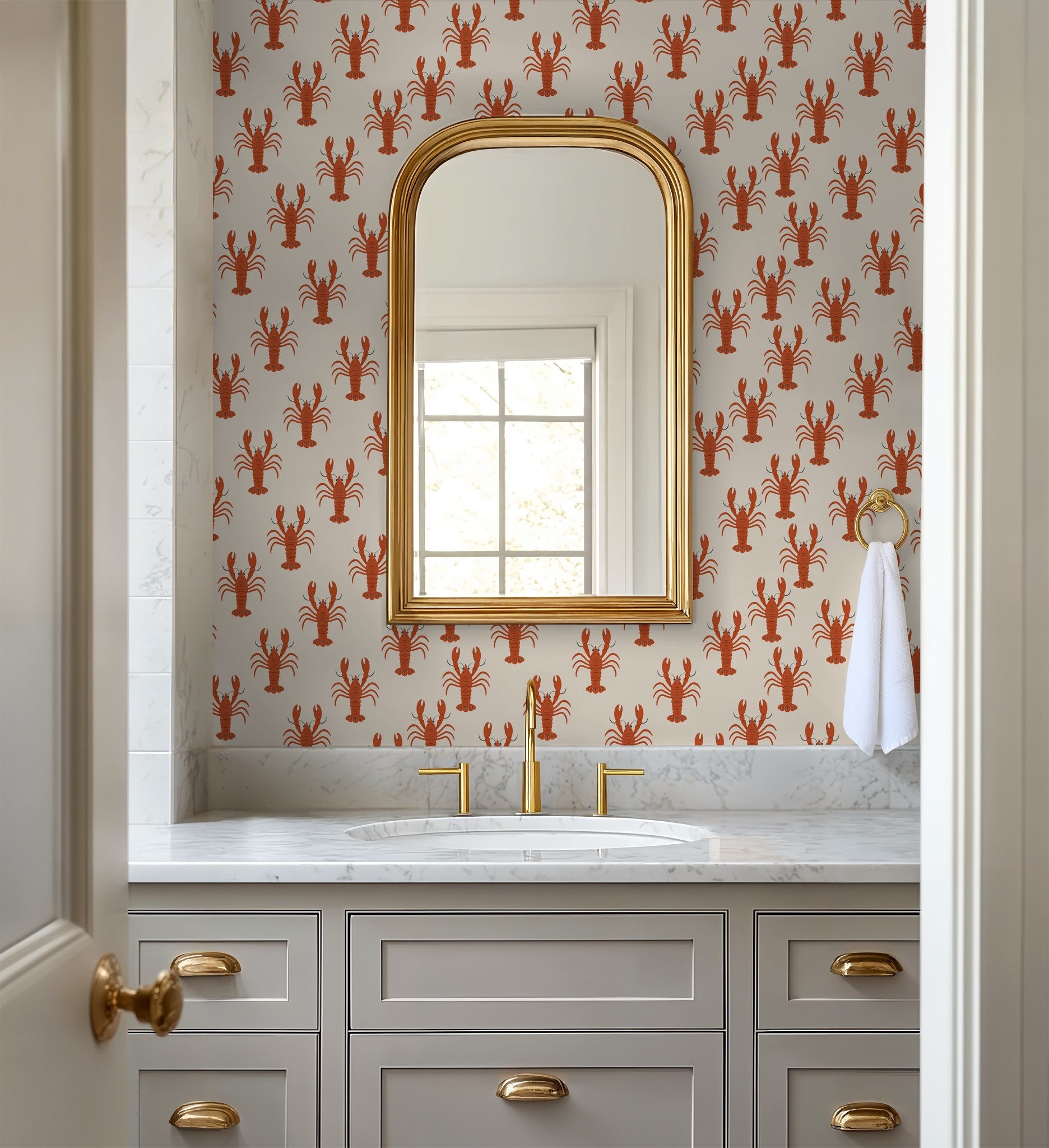 Bathroom with lobster motif wallpaper on cream background, gold accents, and marble countertop.