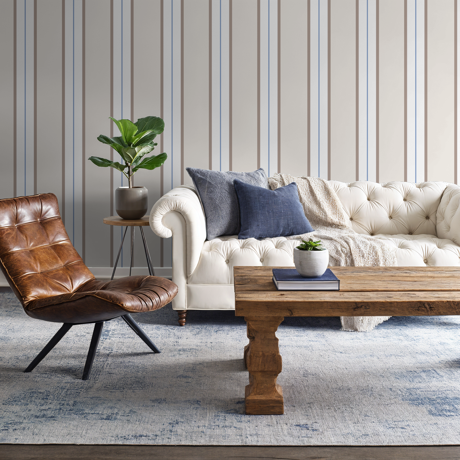 Modern living room with Montclair Stripes blue wallpaper, white sofa, and brown chair.
