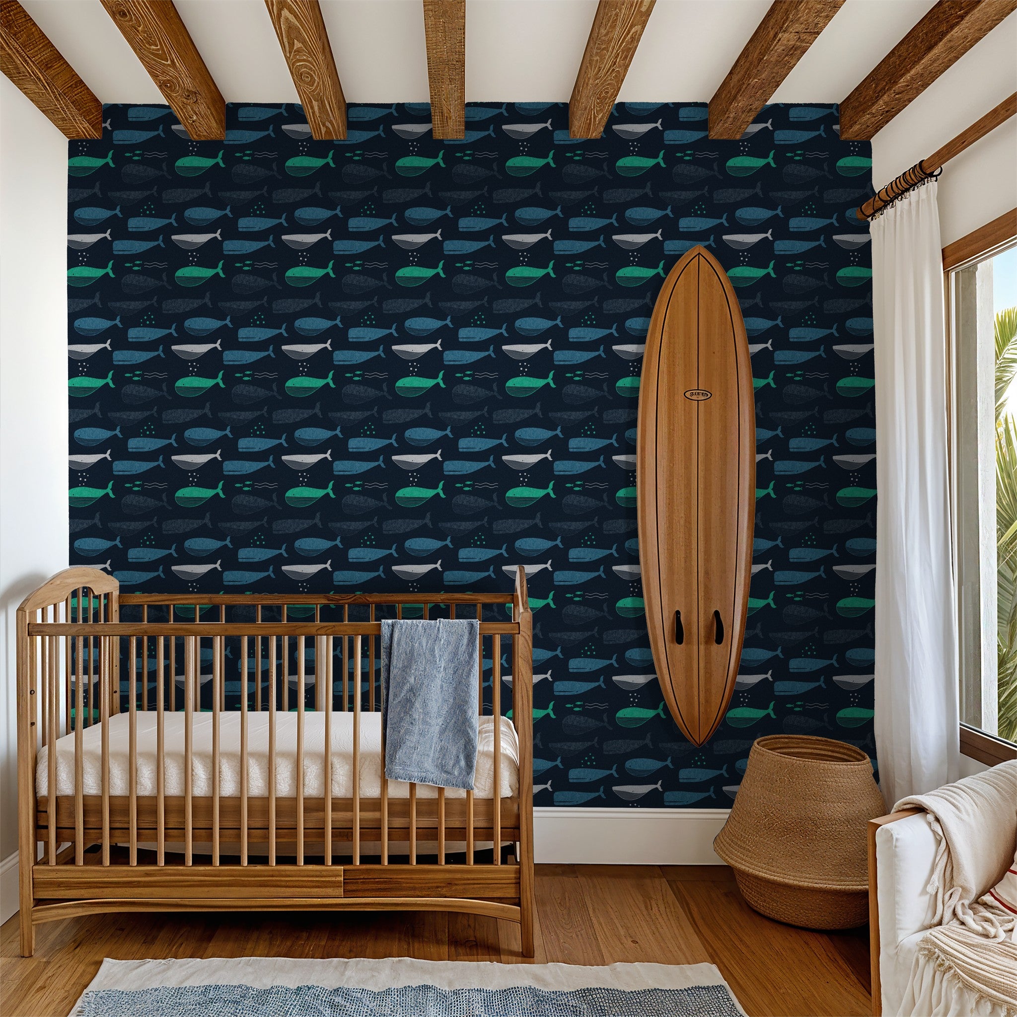 Navy whale wallpaper in nursery with crib and surfboard decor