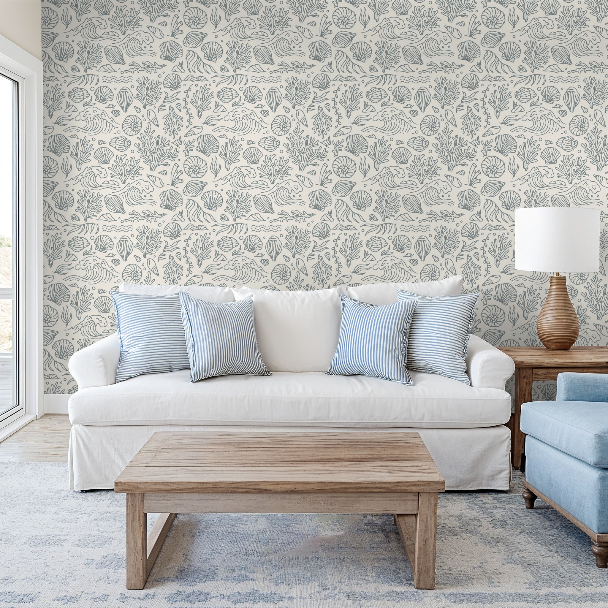 Coastal-themed living room with dusty blue and cream marine life wallpaper, white sofa, and wooden furniture.