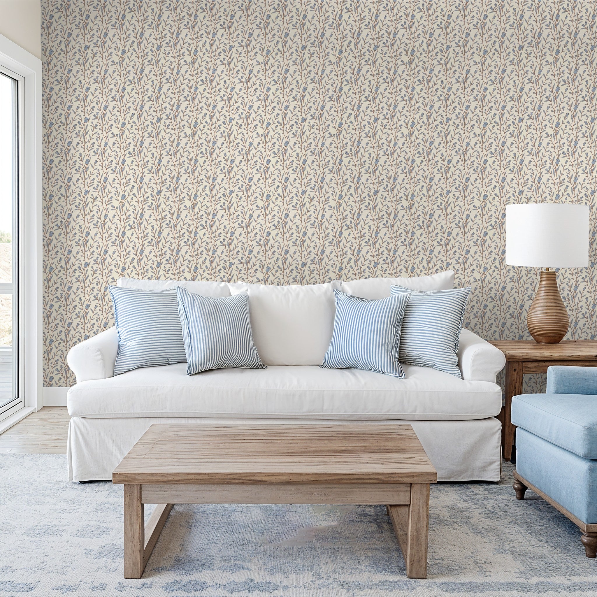 Thistle & Thread wallpaper with blue and brown floral pattern in a cozy living room.
