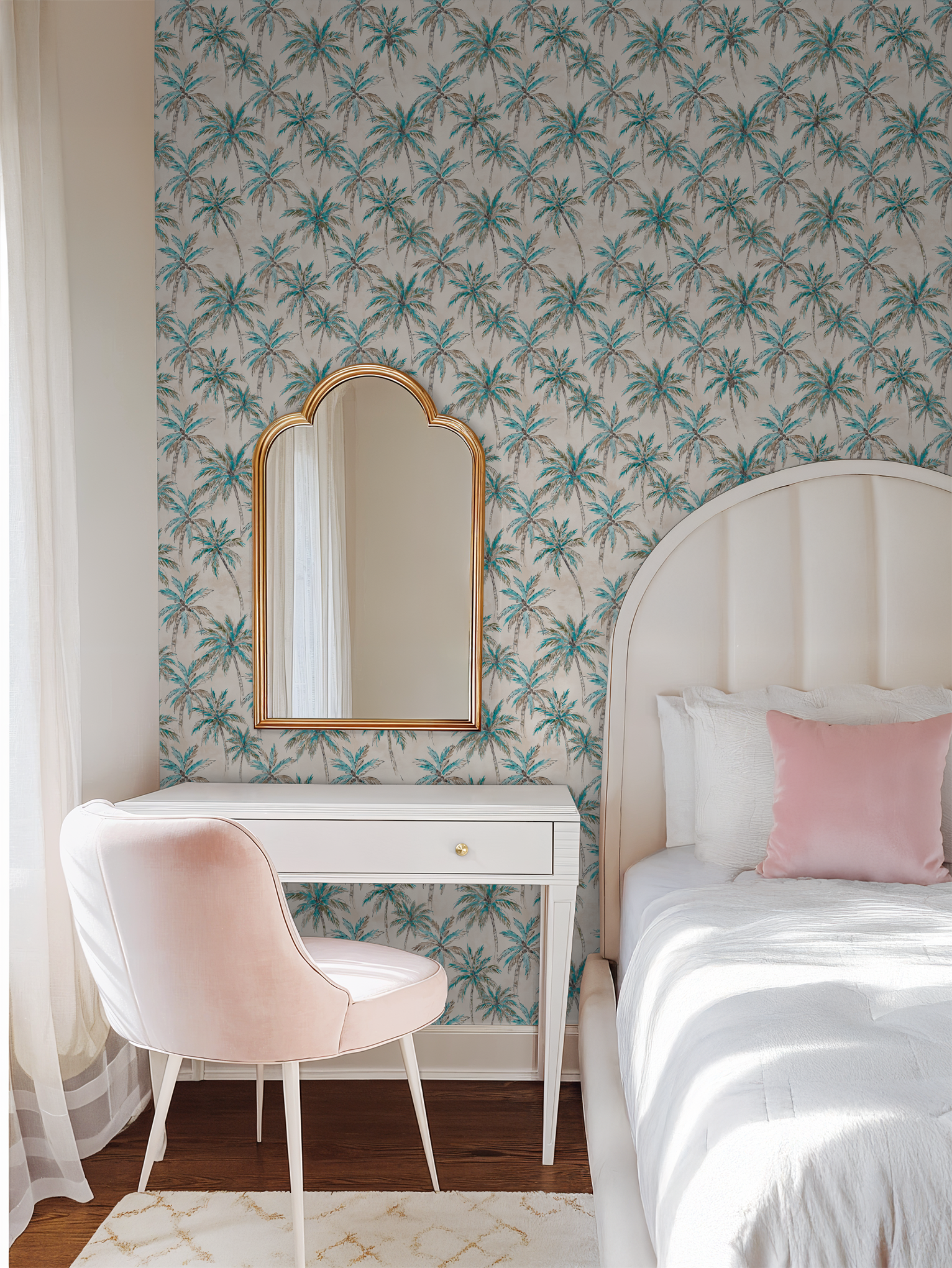 Tropical palm tree wallpaper in a serene bedroom with pink chair and white desk.