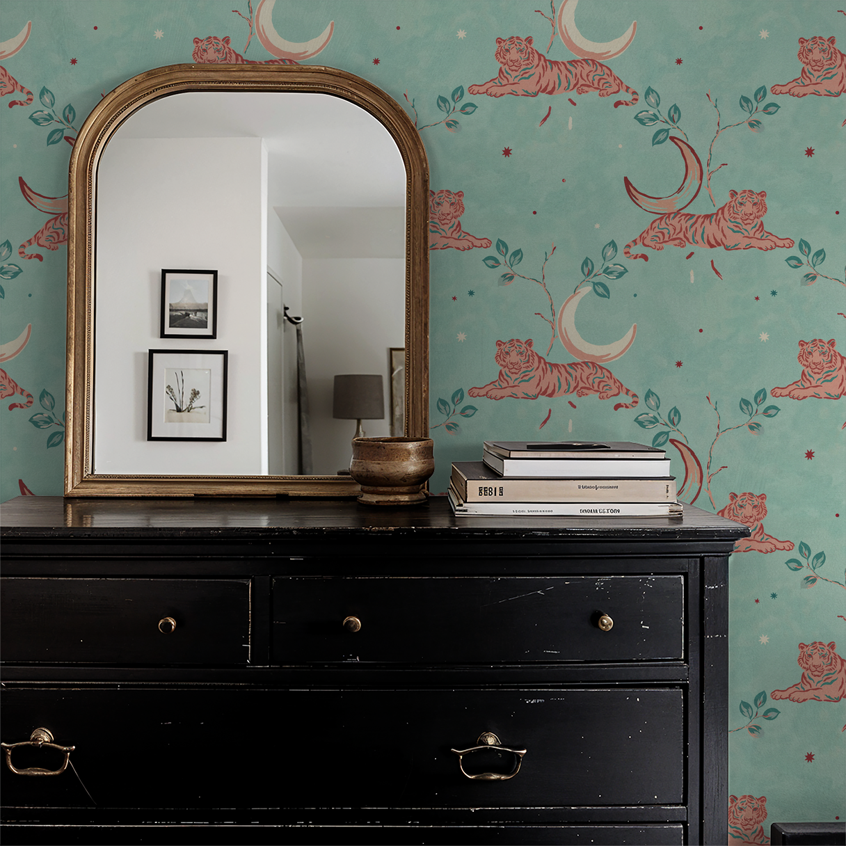 Whimsical tiger and moon wallpaper in serene aqua with coral accents behind black dresser and mirror.