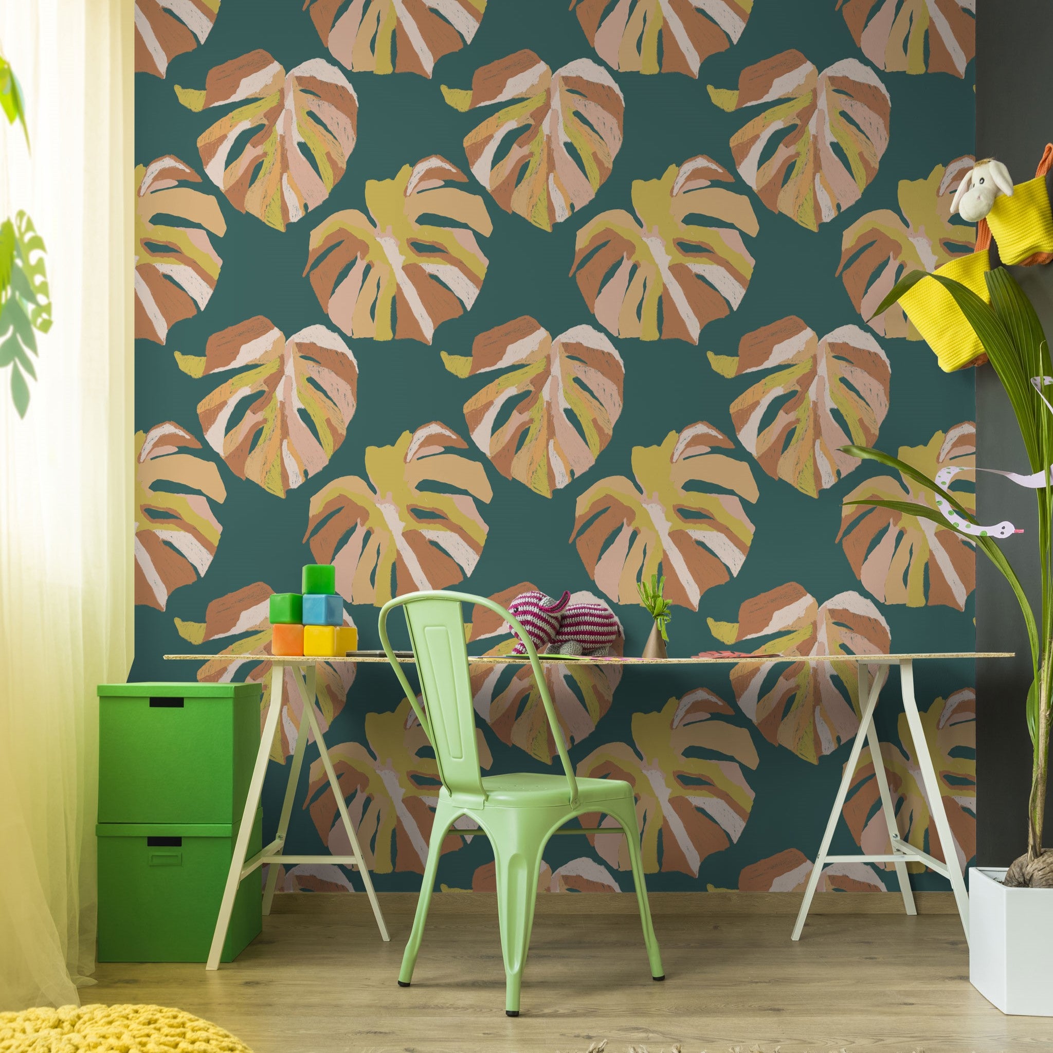 "Wall Blush Monstera Wallpaper in a vibrant home office setting with stylish decor, highlighting green leaf patterns."