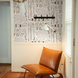 "Wall Blush Trail Blazer (Cream) Wallpaper in a cozy reading nook with leather chair and floor lamp."