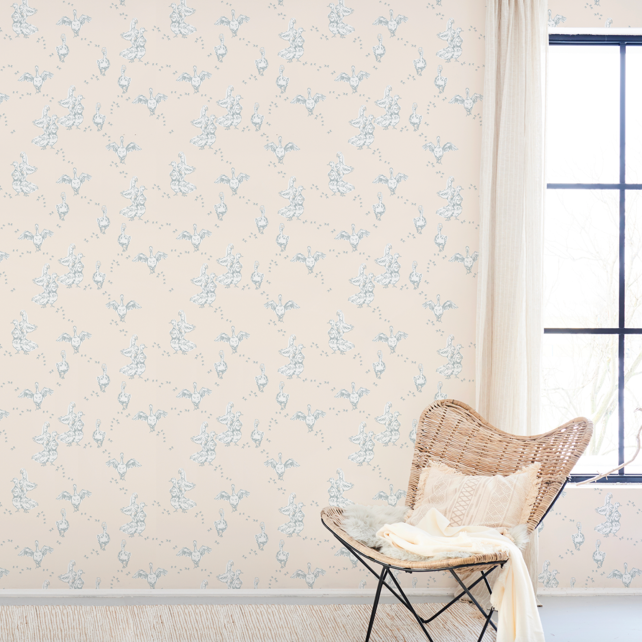 "Wall Blush's Abigail (Cream) Wallpaper in a cozy sunlit room with wicker chair accentuating the elegant decor."