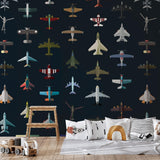 Wall Blush Aviator Wallpaper in children's playroom featuring colorful airplane designs and themed cushions.

