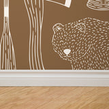 "Wall Blush's Trail Blazer (Brown) Wallpaper installation depicting bear and trees in a cozy room setting, ideal for home decor."