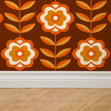 Alt: "Wall Blush Marigold Wallpaper in a modern living room, vibrant orange floral pattern focus."