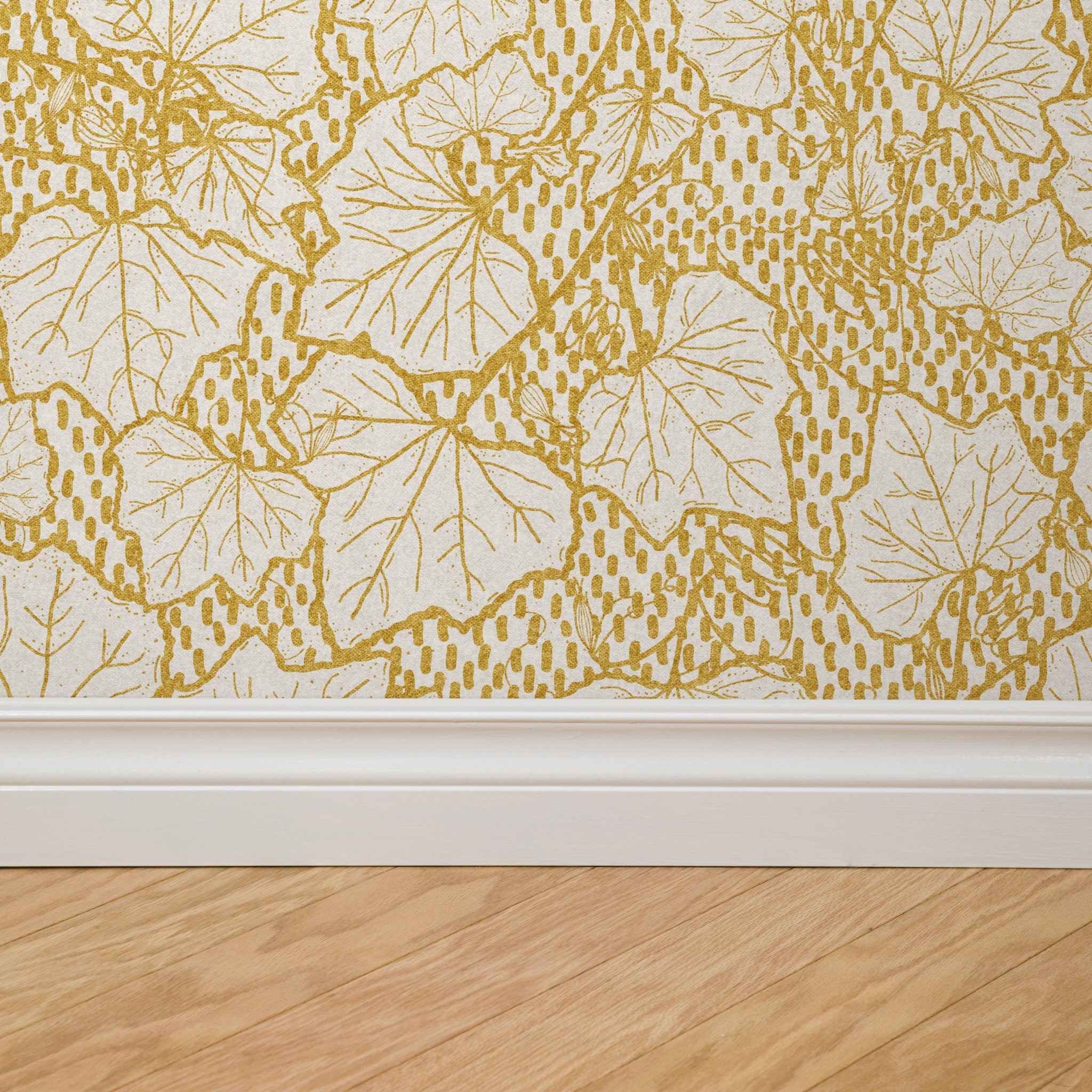 Heath Wallpaper by Wall Blush in a room with detailed golden leaf pattern on lower wall space.