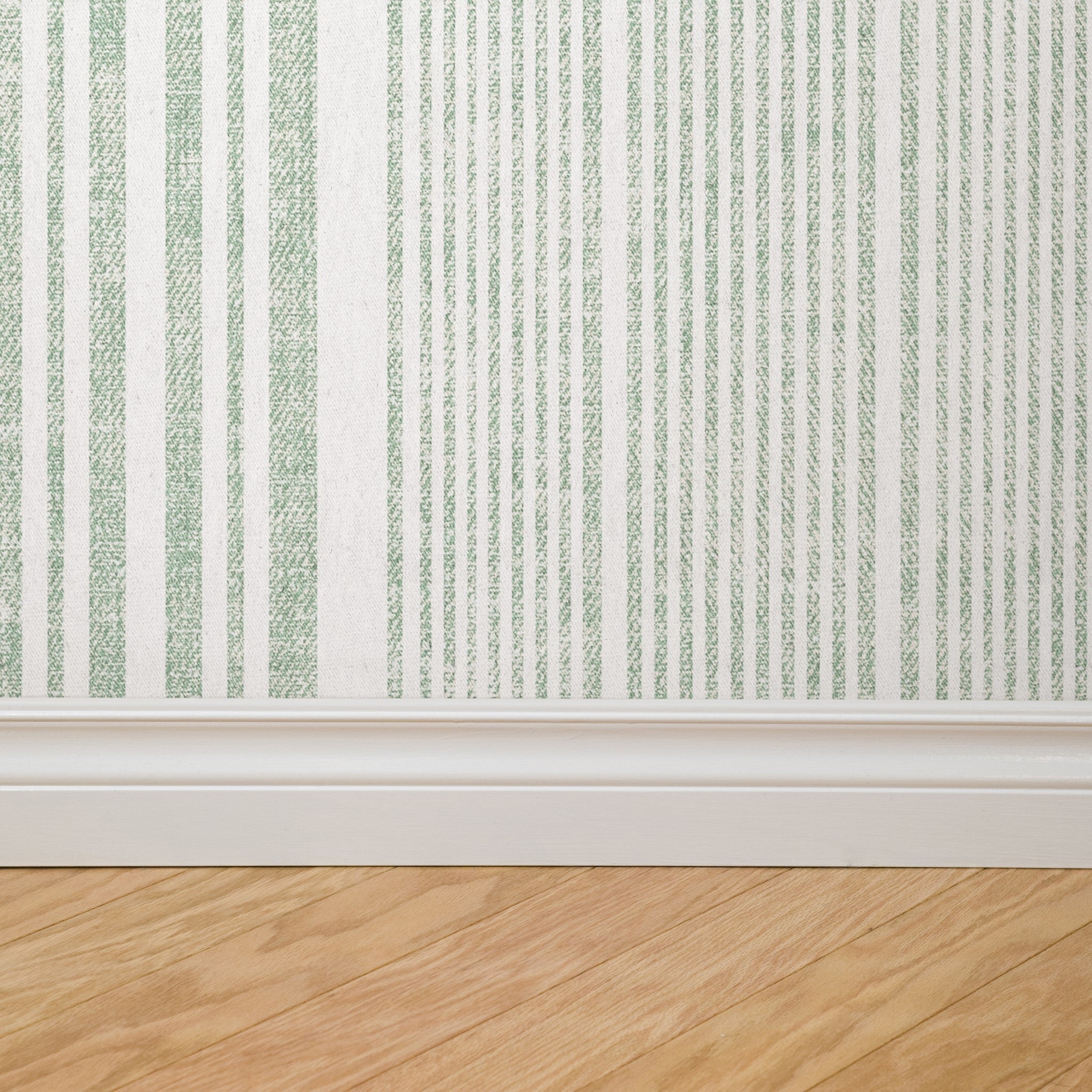 "Wall Blush Small Town Wallpaper in a modern living room, highlighting elegant green vertical stripe pattern."