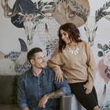 "Wall Blush's Lawless Rose Wallpaper in a modern living room with a cozy couple smiling."