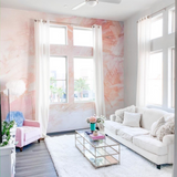 "The Nora Mural Wallpaper by Wall Blush, featuring pink abstract design in a stylish living room setting."