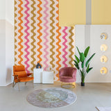 "Modern living room with Polly Wallpaper by Wall Blush featuring colorful wavy design, stylish decor, and accent chairs."