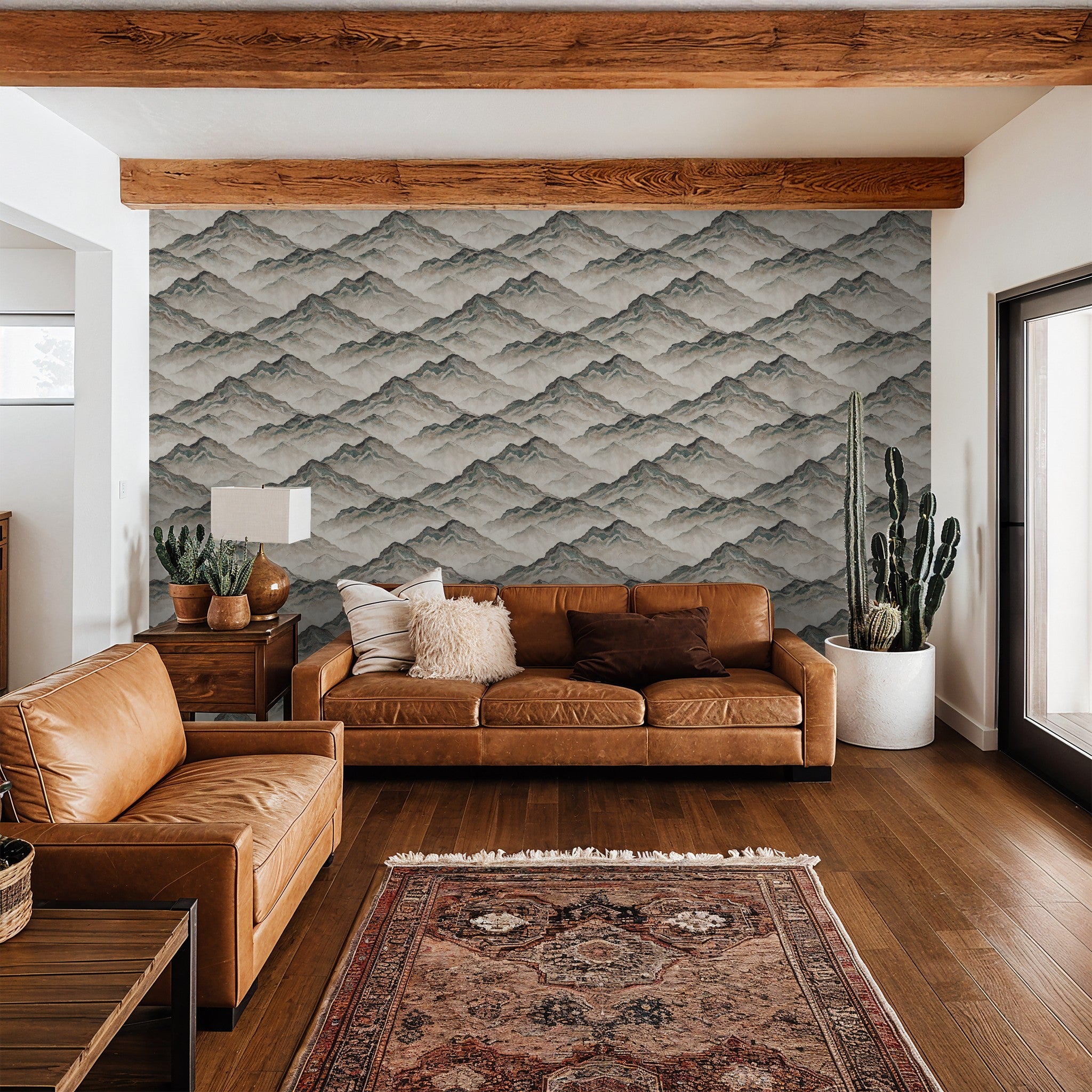 Aurith mountain pattern wallpaper in earthy tones in a cozy living room with leather sofas.