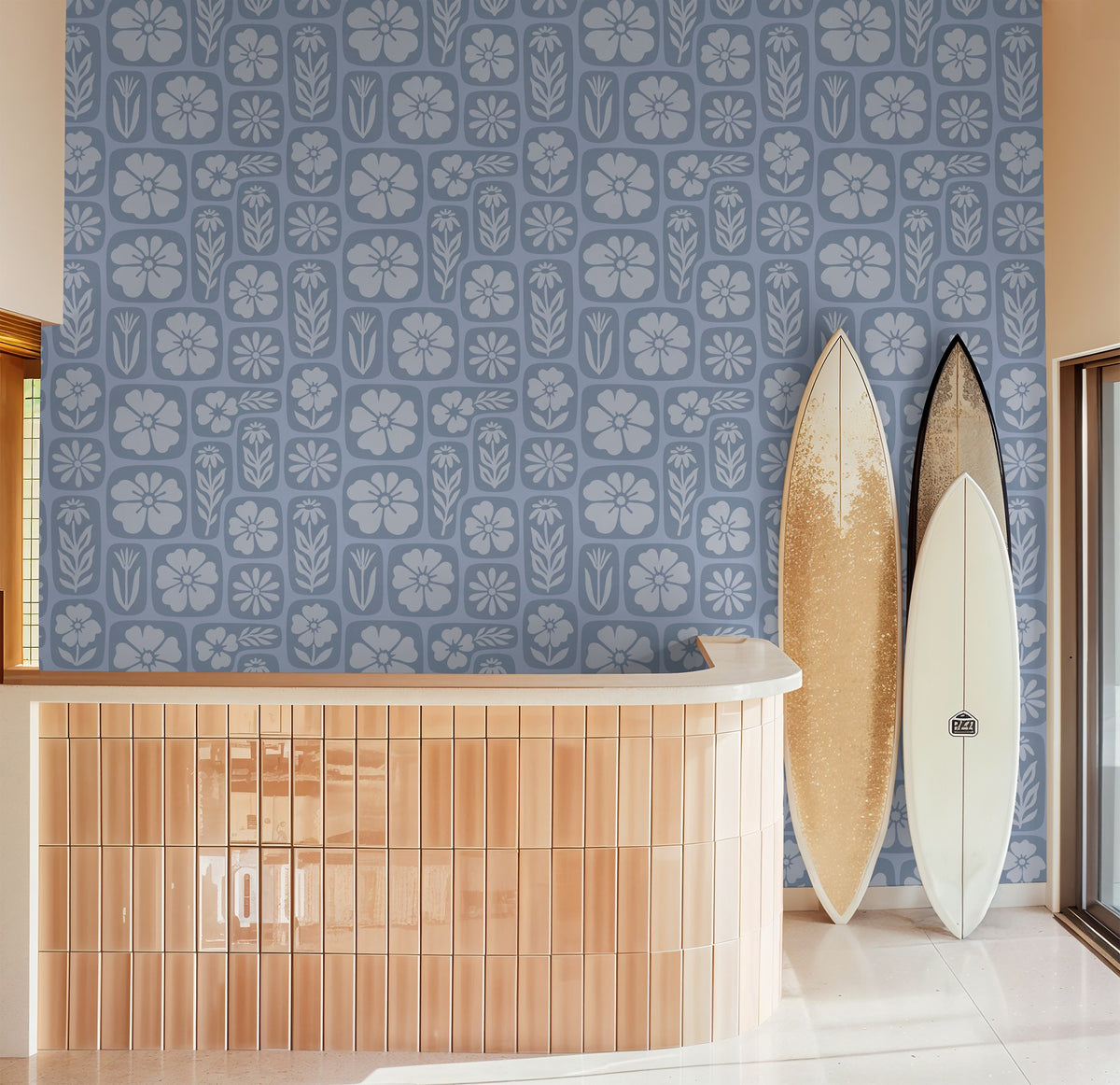 Blue floral wallpaper with botanical motifs in a modern room with surfboards.
