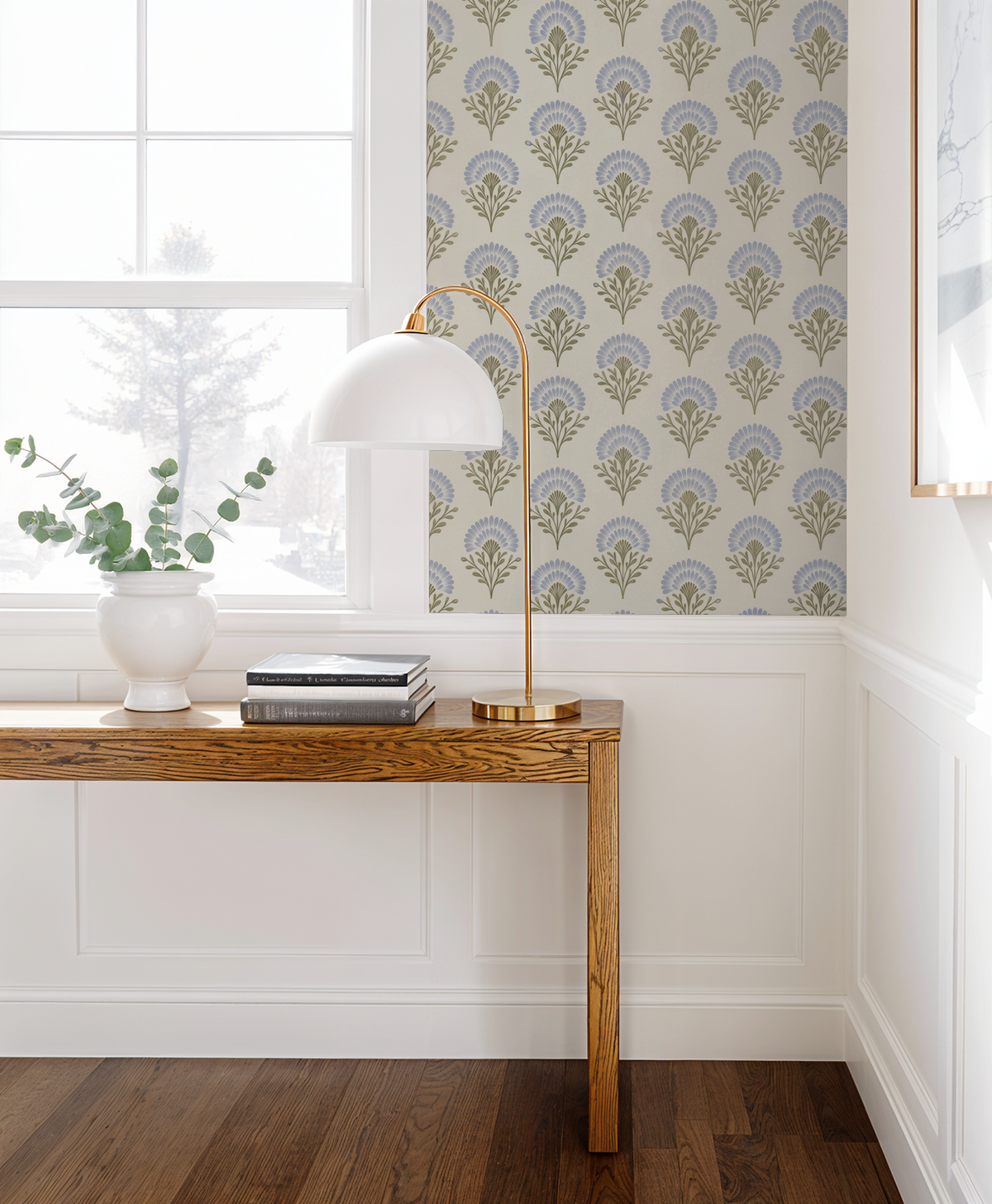 Elegant blue floral wallpaper in a bright living room with wooden table and lamp.