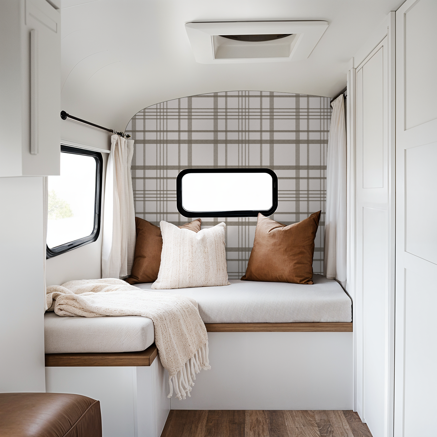 Brown plaid wallpaper in cozy camper with pillows and throw blanket.