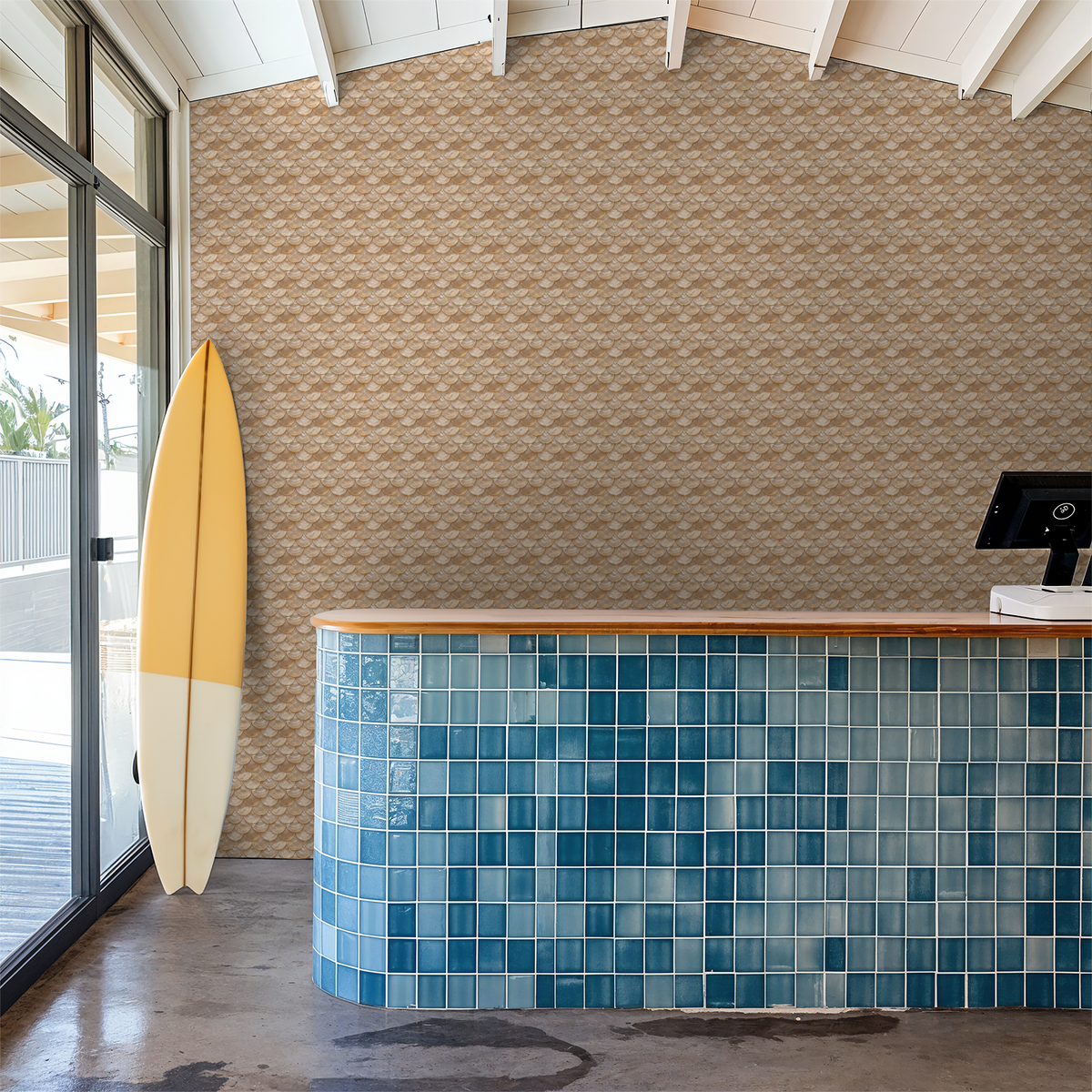 Calypso wallpaper with scallop pattern in warm tones behind a blue-tiled counter and surfboard.