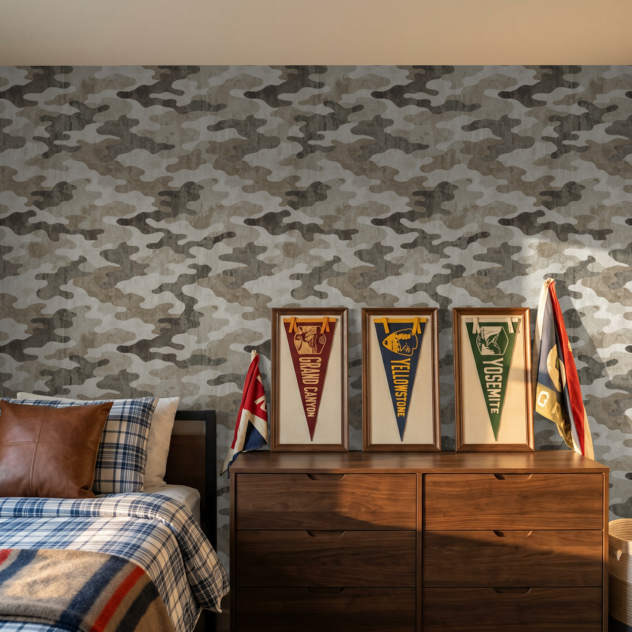 Camouflage wallpaper in earth tones in a cozy bedroom with wood dresser and flags.