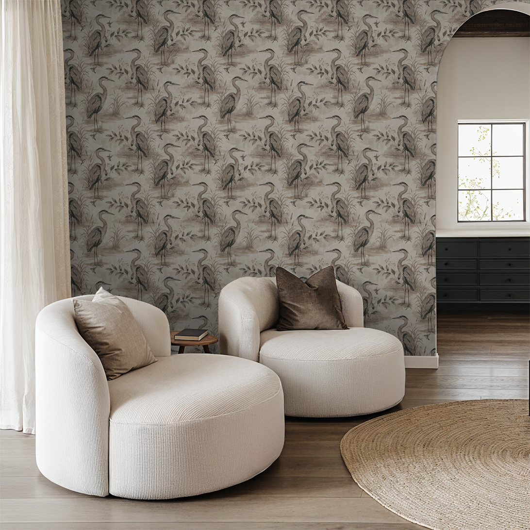 Heron Lake wallpaper with herons and foliage in taupe tones in a cozy living room.