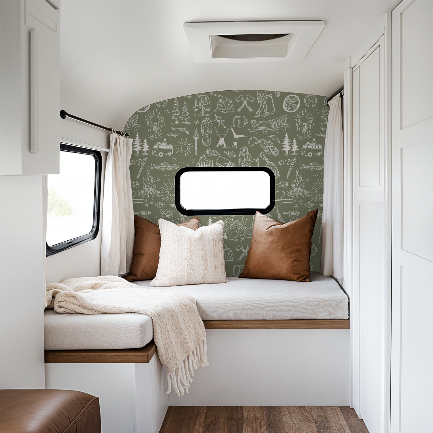 Olive green wallpaper with white camping motifs in a cozy RV interior.