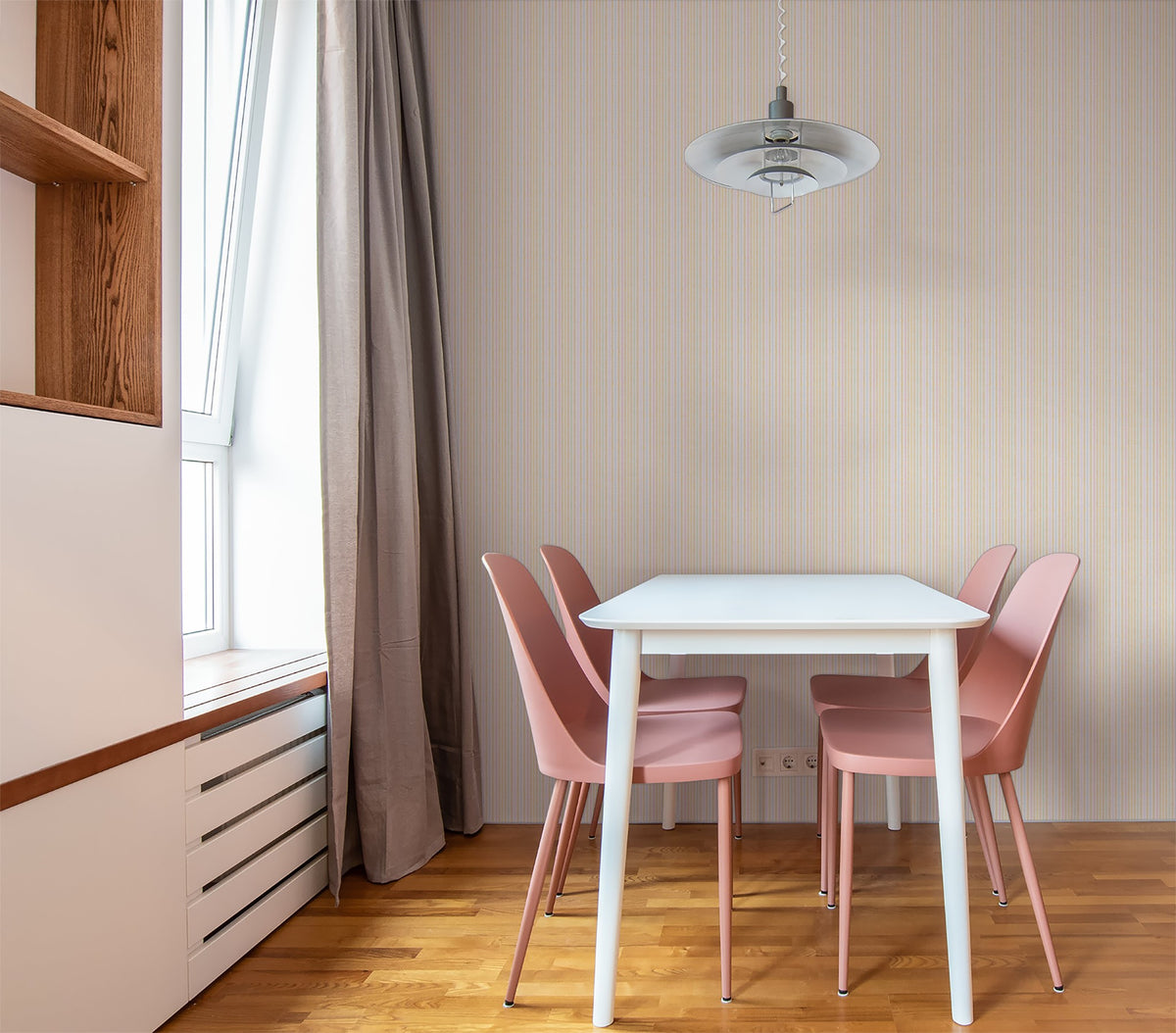 Pastel striped wallpaper in dining room with pink chairs and white table.
