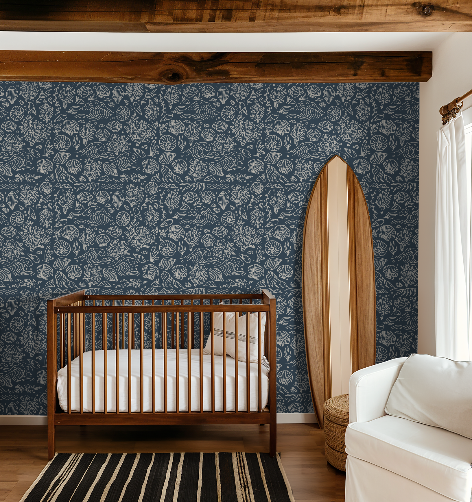 Slate blue wallpaper with white shell and coral pattern in a nursery with wooden crib and surfboard decor.