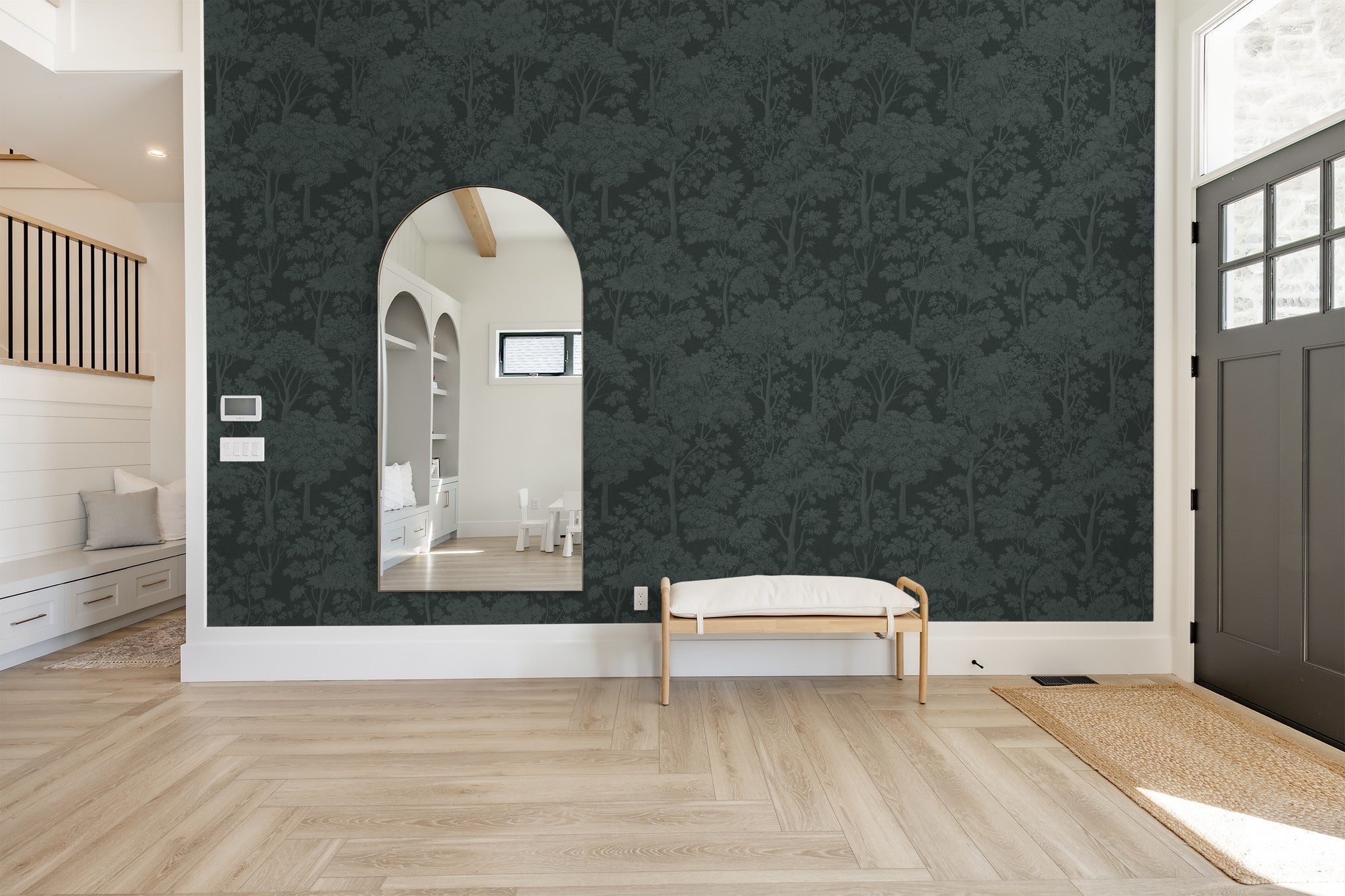 Teal tree canopy wallpaper in modern living room with mirror and bench.