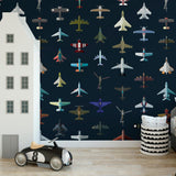 Alt: Kid's room with vibrant Aviator Wallpaper by Wall Blush, featuring colorful planes on a navy background, focus on wall decor.
