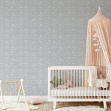 "Wall Blush Baba Blue Wallpaper in cozy nursery setting with crib and soft decor, emphasizing the elegant wall design."