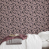 Cheetah Blush Wallpaper by Wall Blush in cozy bedroom setting, showcasing stylish pink animal print design.
